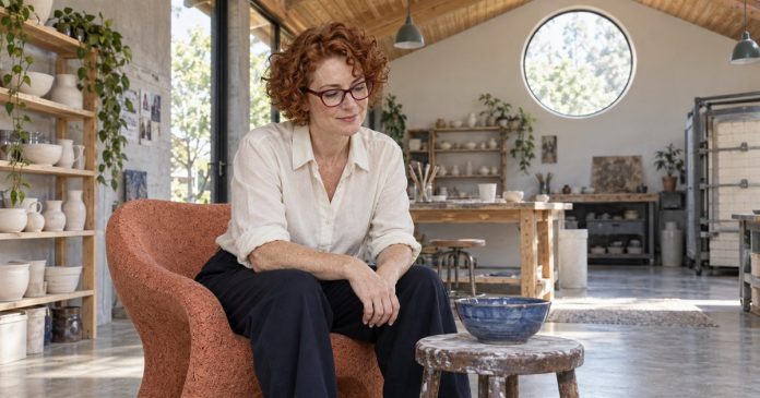 Woman with auburn curls noticing a blue bowl during a pause in a ceramics studio